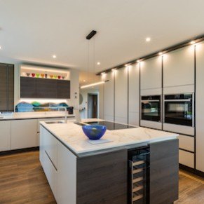A sleek navy and white island kitchen with bar seating and pendant lighting.