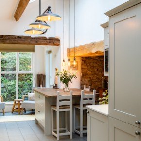 A country style kitchen with dark wood cabinets and and white tops island, hidden seating and a range cooker.