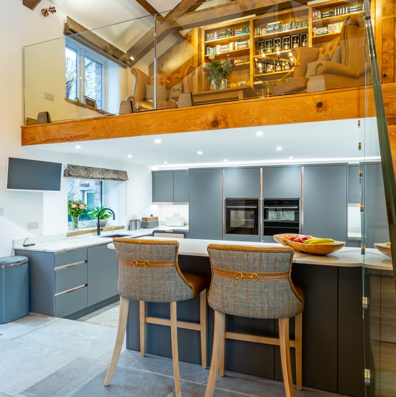Grey kitchen in converted barn, under a mezzanine floor